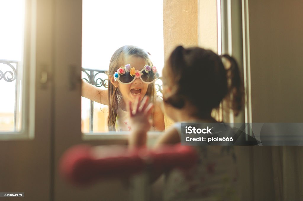 Baby girls together by a window Baby girls together having fun by a window Eccentric Stock Photo