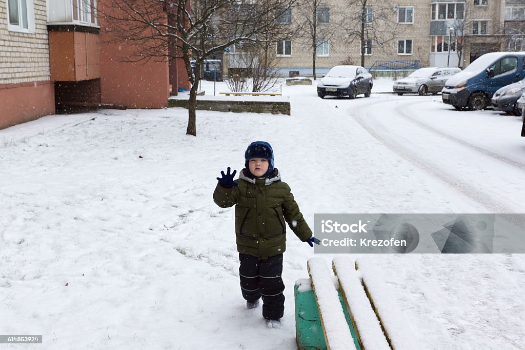 boy playing on a snowy street warm winter dressed boy playing on a snowy street Car Stock Photo