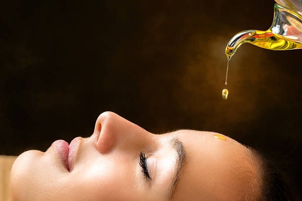Aromatic oil dripping on female face. Macro close up portrait of young woman at ayurvedic massage session with aromatic oil dripping on face. aromatherapy oil photos stock pictures, royalty-free photos & images