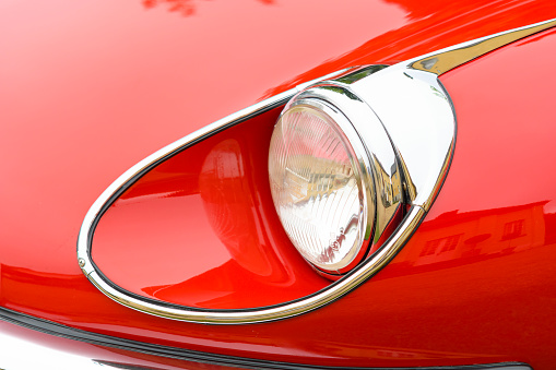 Jüchen, Germany - August 5, 2016: Jaguar E-Type Roadster or Jaguar XK-E 1960s convertible sports car headlight. The E-type is an iconic British sports car produced by Jaguar from 1961 until 1975 and was available as coupe or convertible. The car is on display during the 2016 Classic Days at castle Dyck. 