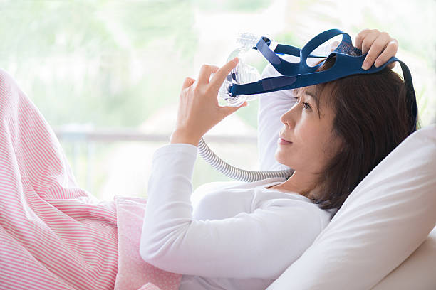 mujer acostada en la cama con máscara de cpap, terapia de apnea del sueño - apnea del sueño fotografías e imágenes de stock