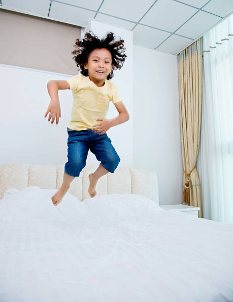 istock Little boy jumping on the bed 614857856