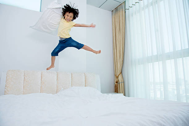 istock Little boy jumping on the bed 614858080