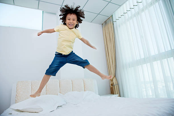 istock Little boy jumping on the bed 614858186