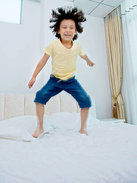 istock Little boy jumping on the bed 614858234