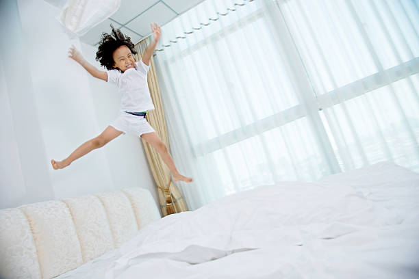 istock Little boy jumping on the bed 614858300