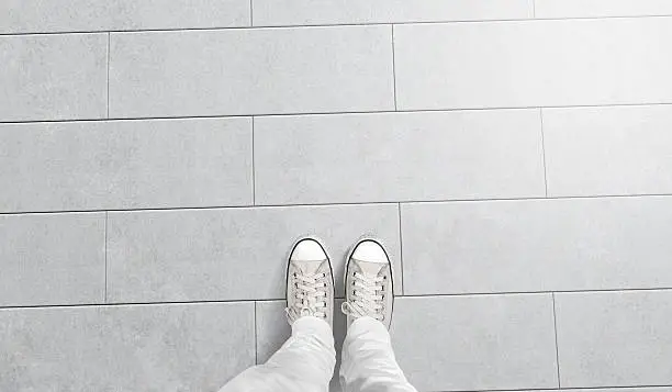 Person taking photo of his foots stand on blank floor, isolated, top view, clipping path. Ground design mock up. Man wear gumshoes and watching down. Deck flooring mockup template.