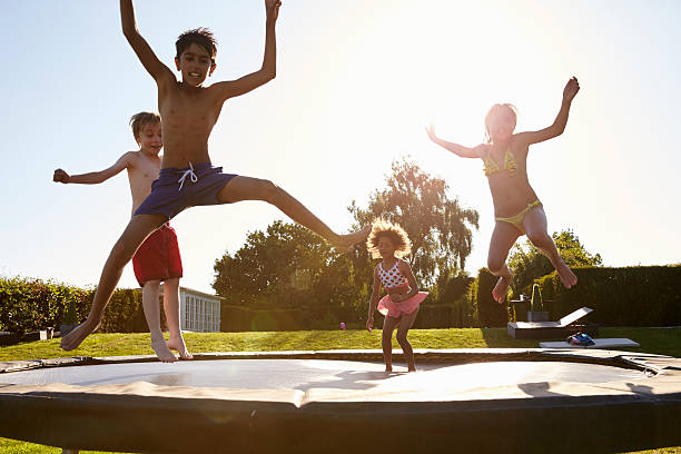 Group Of Children Having Fun Jumping On Outdoor Trampoline