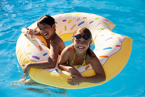 istock Children Having Fun With Inflatable In Outdoor Swimming Pool 614859916