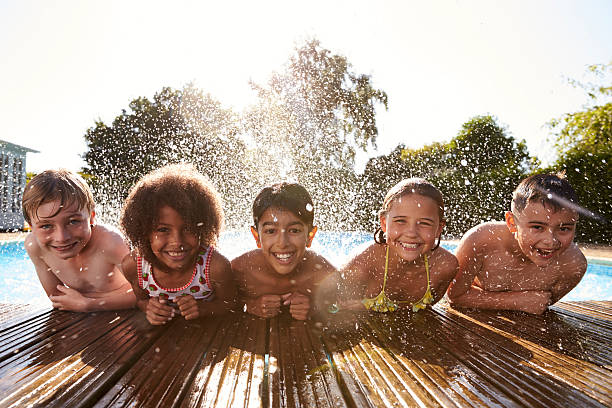 Portrait Of Children Having Fun In Outdoor Swimming Pool Portrait Of Children Having Fun In Outdoor Swimming Pool one piece swimsuit photos stock pictures, royalty-free photos & images
