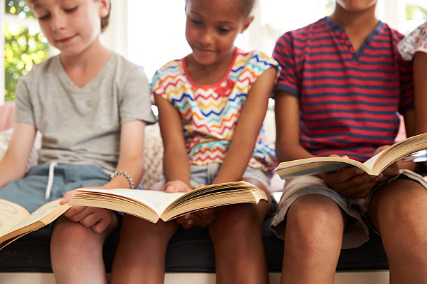 istock Close Up Of Children Reading On Window Seat 614860120