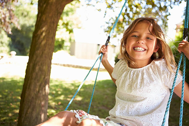 istock Portrait Of Young Girl Playing On Tree Swing 614860232