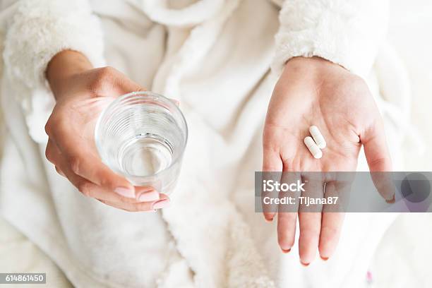 Woman Holding A Glass Of Water And Pills Detail Stock Photo - Download Image Now - Capsule - Medicine, Pill, Medicine