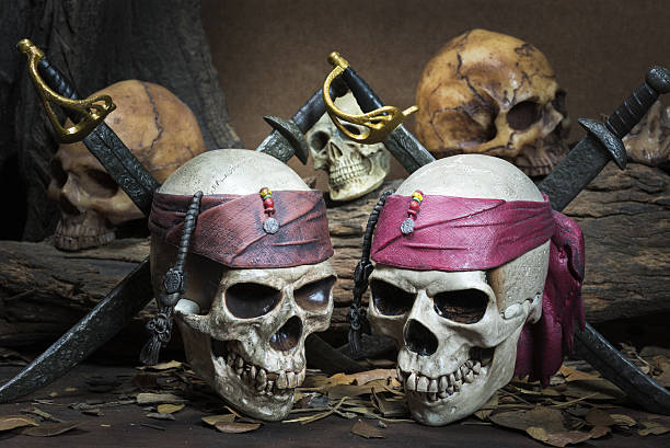 istock Two Pirate skull over three human skull in the forest 614861766