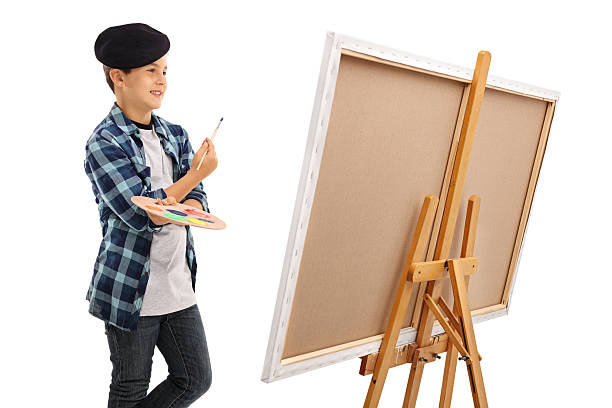 istock Boy looking at canvas with paintbrush and palette 614862802