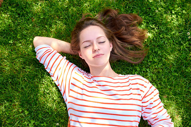 istock Beautiful girl lying in the grass 614865792