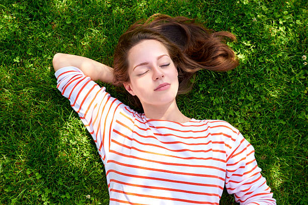 istock Beautiful girl lying in the grass 614865944