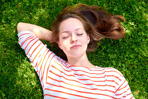 istock Beautiful girl lying in the grass 614866038