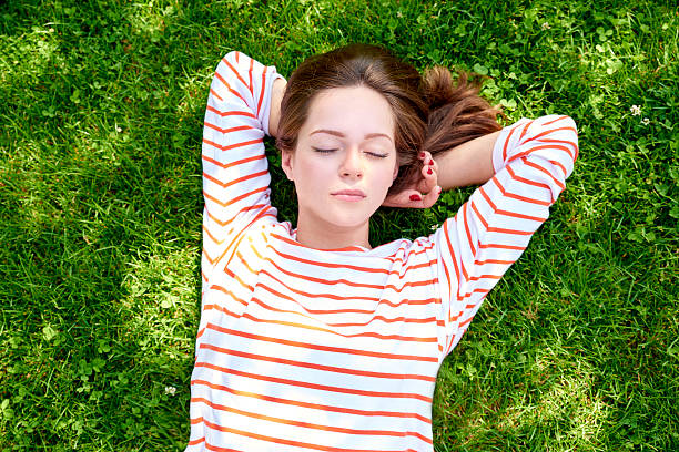 istock Beautiful girl lying in the grass 614866160