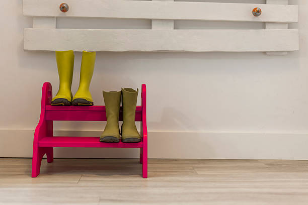 Green boots in a fuchsia steps ladder. Home entrance stock photo