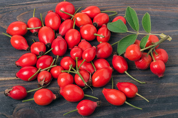 istock fresh rose hips with leaves on a dark wooden background 614866598