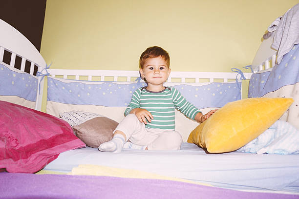 istock Baby sitting in the baby crib 614869886