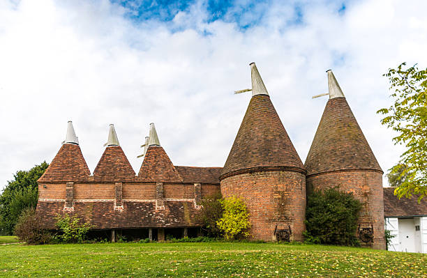 Triple red brick chimney stack on a 16th century house in Kent, England. The roof tiles also betray their age.