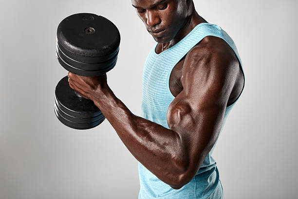 африканская фитнес-модель, осуществляющая с тяжелыми гантелями - flexing muscles men human muscle human arm стоковые фото и изображения
