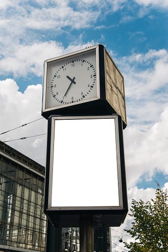 A street billboard with a clock on top of it