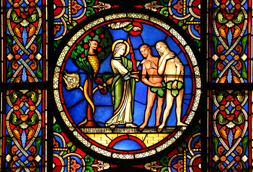 Ely, United Kingdom - September 4, 2007: Stained glass window at Ely Cathedral (UK) depicting Adam and Eve with the Devil and Angel