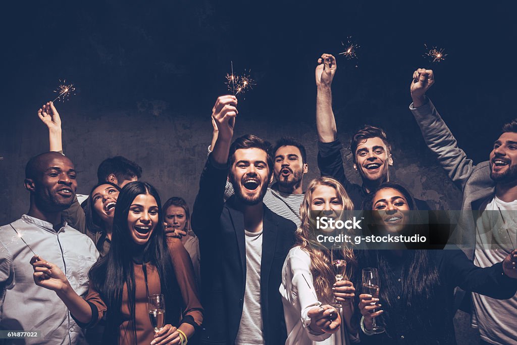 Party with friends. Group of cheerful young people carrying sparklers and champagne flutes Cool Attitude Stock Photo