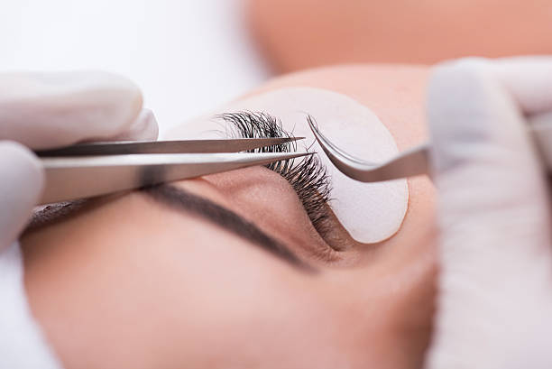 istock Beautiful young woman during eyelash extension 614878264
