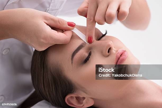Young Woman Tweezing Her Eyebrows In Beauty Saloon Stock Photo - Download Image Now - Waxing - Hair Removal, Eyebrow Waxing, Human Face