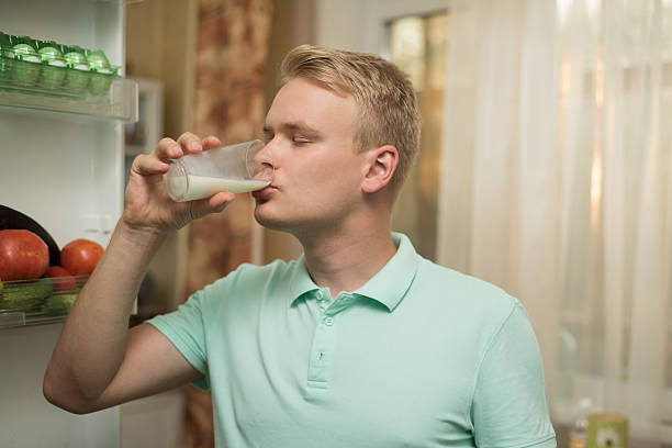 istock Young man drinking milk in the kitchen, standing at the 614951314