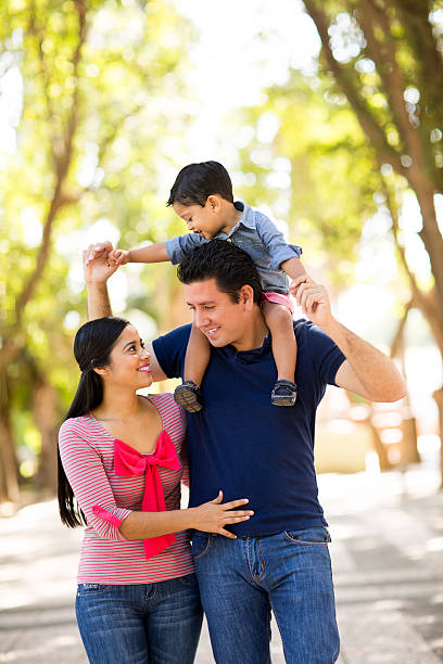 istock Latin father carrying son on shoulders next to mother 614957762