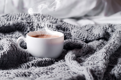 Having a cup of coffee on gray blanket in bed