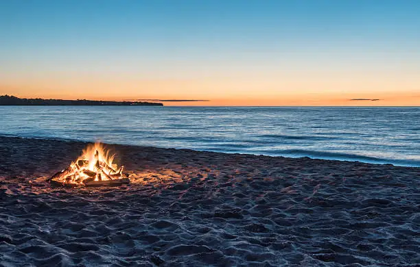 Bonfire on sandy beach at sunset