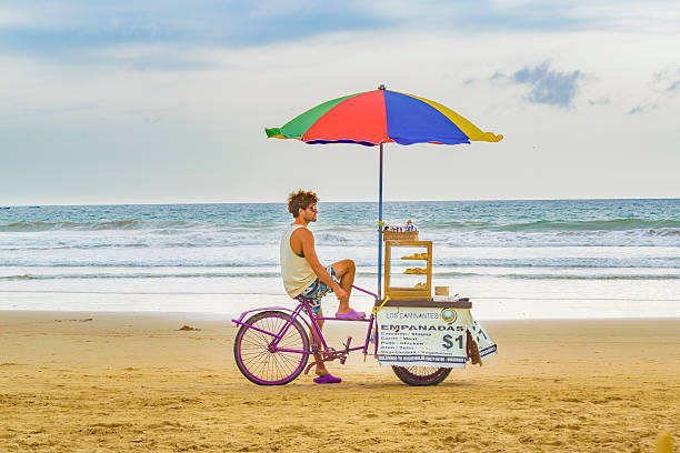 People at Montanita Beach Ecuador Montanita, Ecuador - October 23, 2015: Young adult man selling food at beach in Montanita, the most famous watering place in Ecuador montanita ecuador stock pictures, royalty-free photos & images