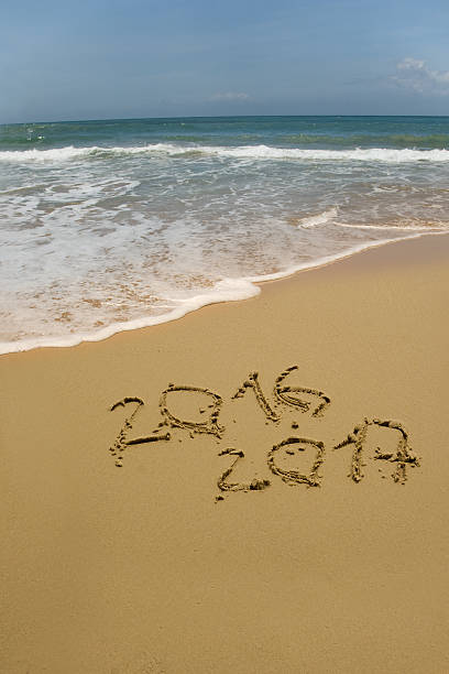 istock year 2016 and 2017 on the sand beach 614967774