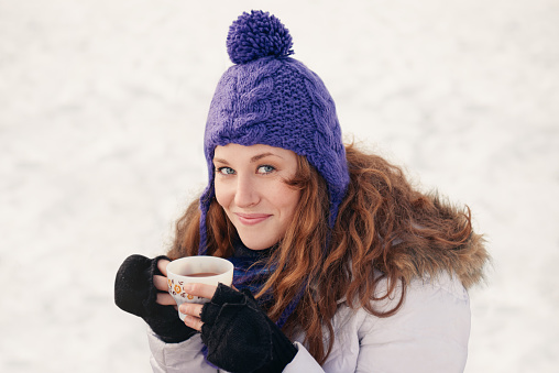 Portrait of one young woman enjoying cocoa in the snow