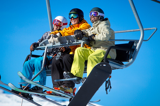 Group of males enjoying the view from chair lift on sunny day.
