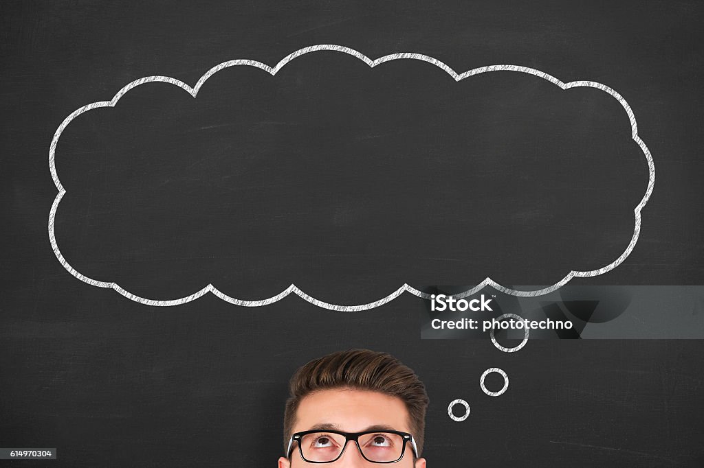 Business man standing next to thought bubble drawn on chalkboard Thought Bubble Stock Photo