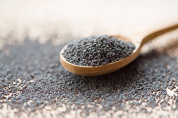Poppy seeds in wooden spoon Wooden spoon with poppy seeds, close-up poppy seed stock pictures, royalty-free photos & images