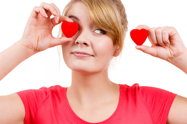 istock Funny woman holds red hearts over eyes 614973170