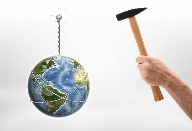 istock Man's hand driving nail into wall with the Earth 614974040
