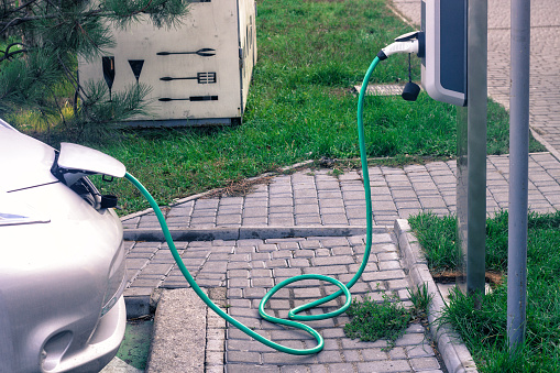 Power supply for electric car charging. Electric car charging station. Close up of the power supply plugged into an electric car being charged.