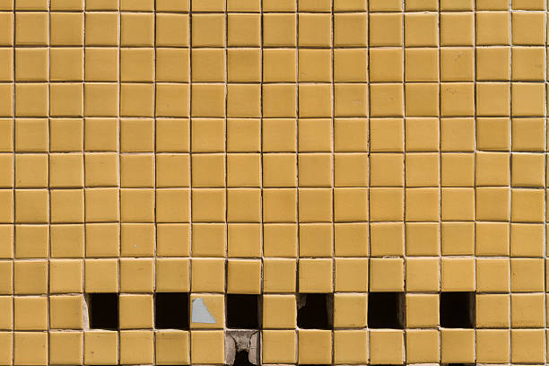 istock Wall surface with small yellow tiles and holes 614974846
