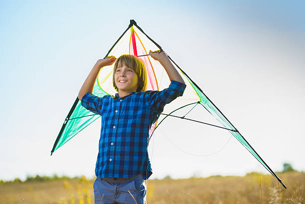 istock Happy and smiling boy playingin with kite outdoor 614977174