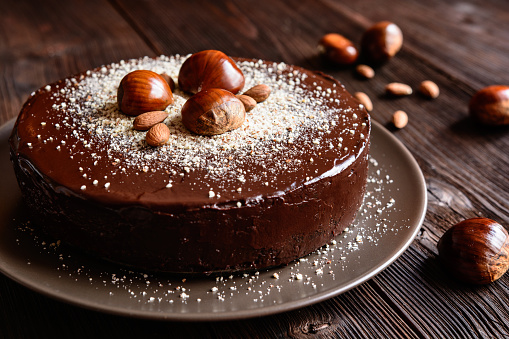 Stock photo showing elevated view of slices of chocolate and cherry cake, Black Forest gateau, red velvet, rainbow cake, coffee and marbled chocolate gateau displayed on a circle of greaseproof parchment paper against a marble effect background.