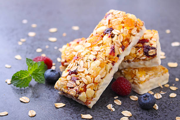 healthy snack, muesli bars healthy snack, muesli bars with raisins and dried berries on a black background granola stock pictures, royalty-free photos & images